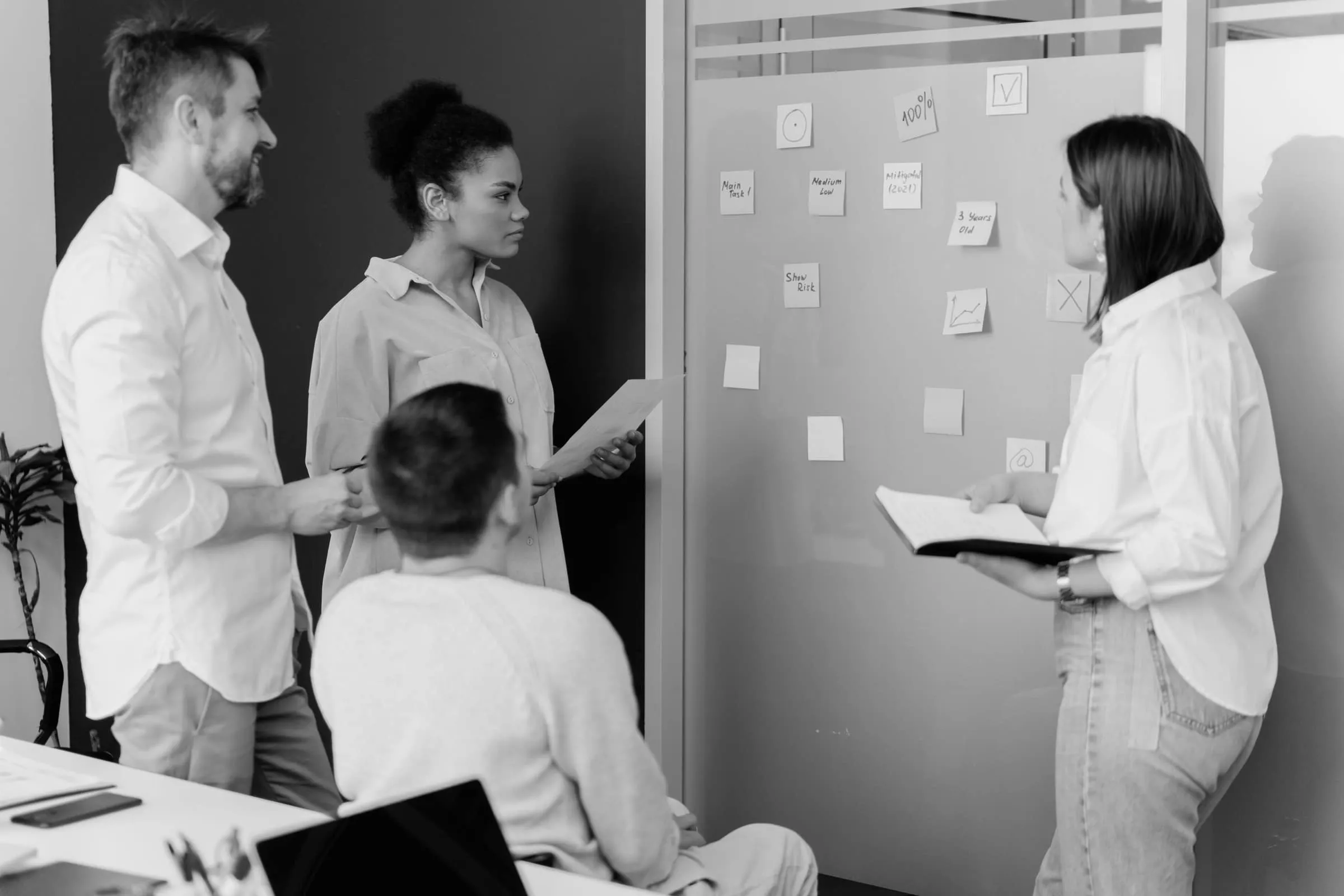 A group standing at a wall covered in sticky notes, planning together