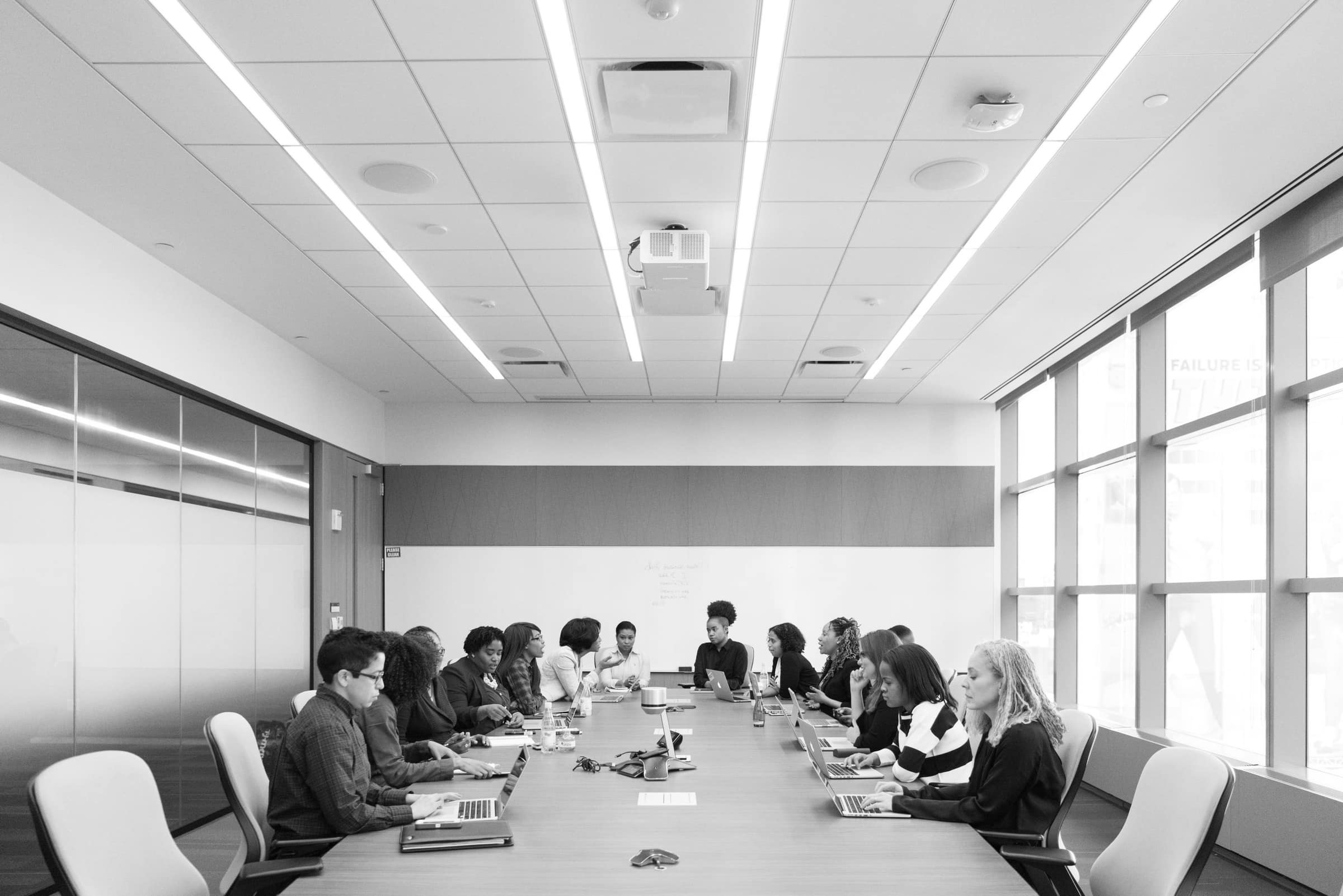 A long boardroom table with a team seated along both sides in discussion