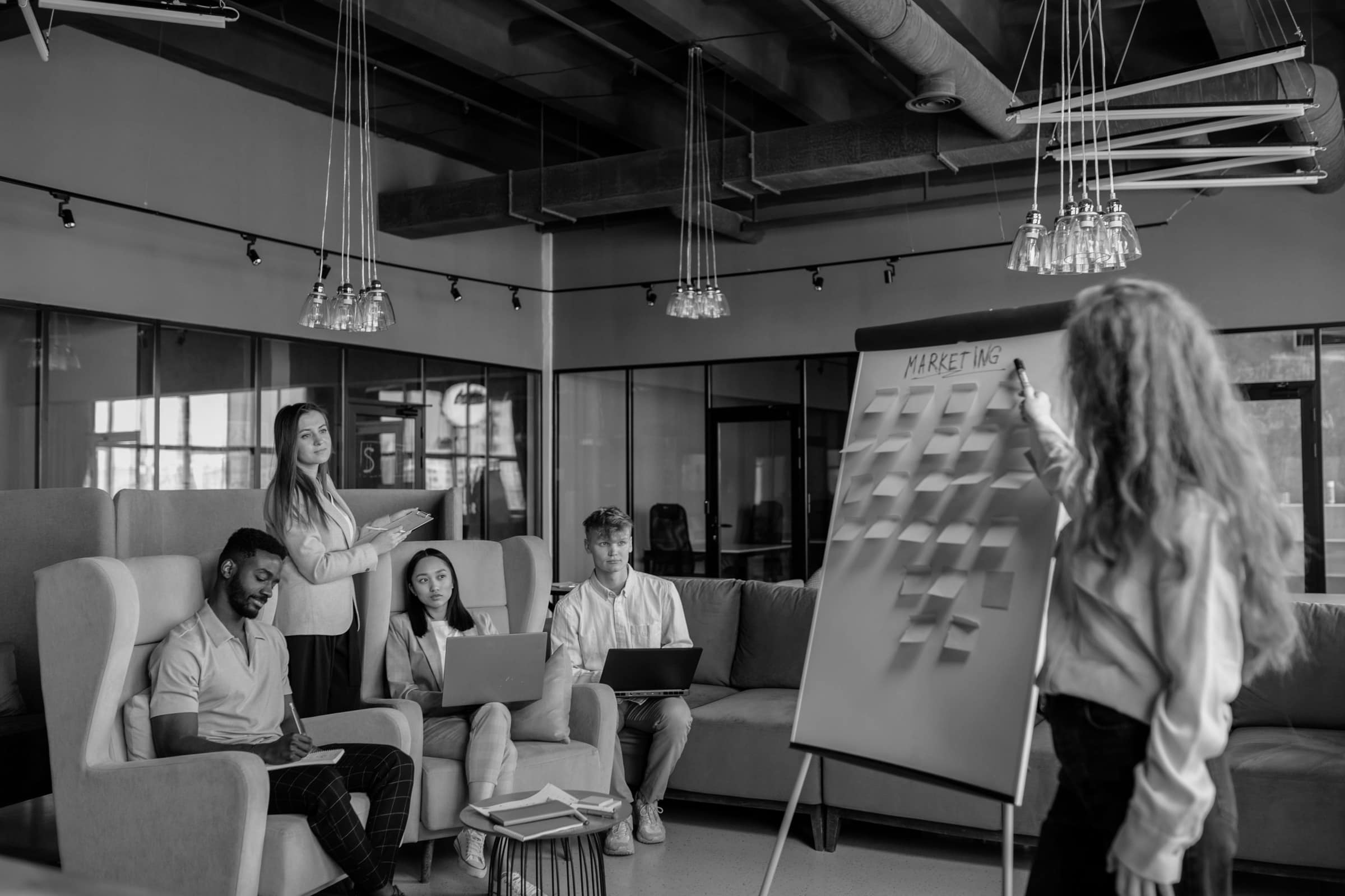 A team sitting on sofas around a flip chart in an open office