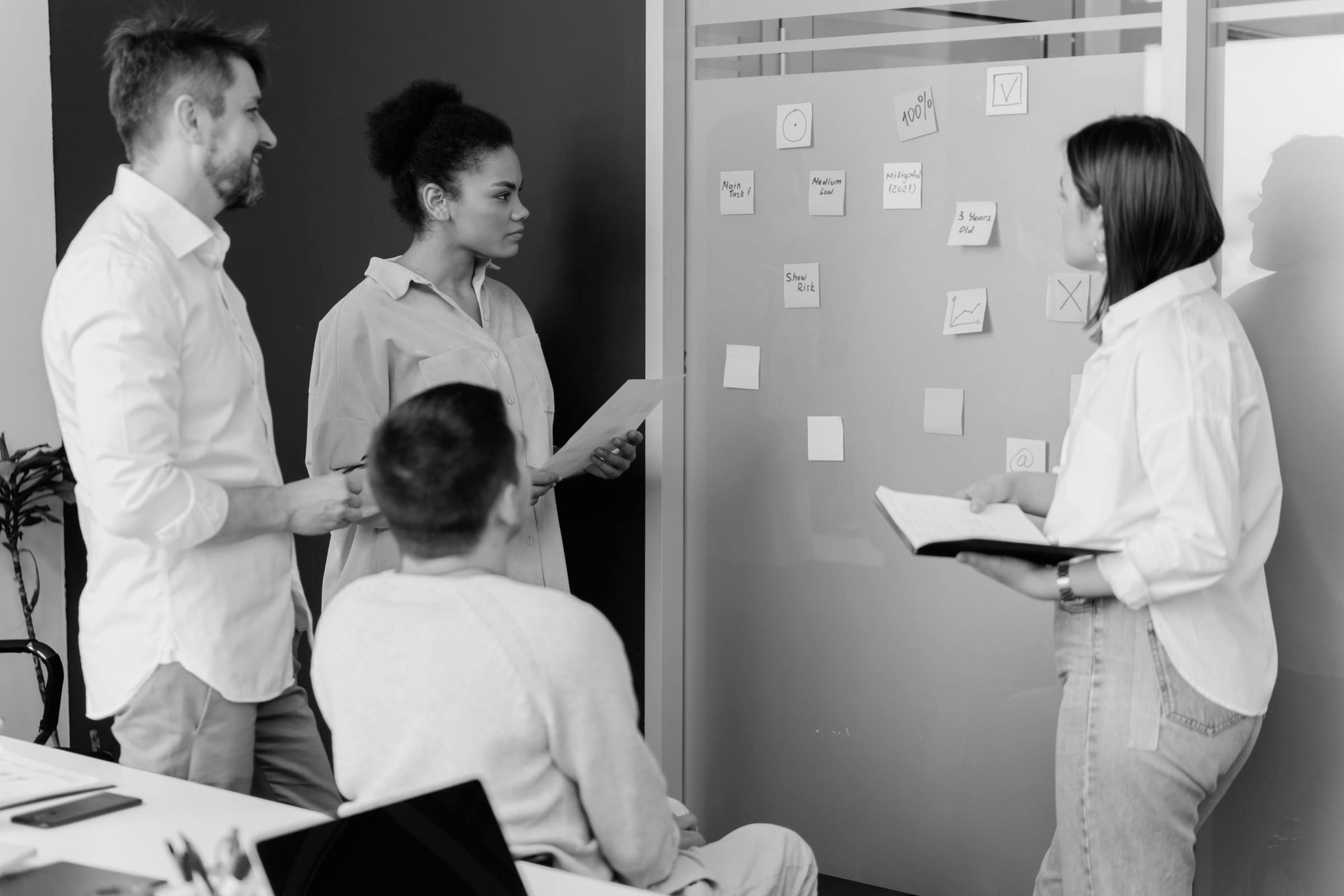 A group standing at a wall covered in sticky notes, planning together