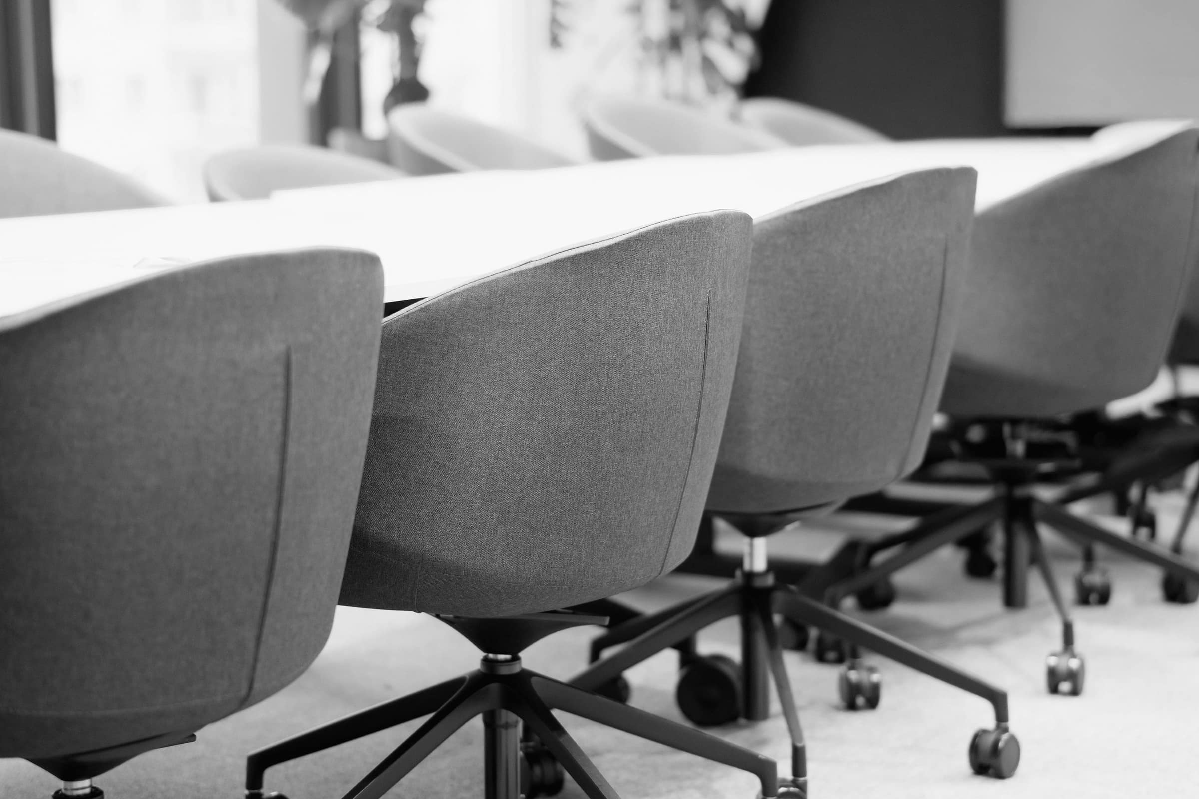 A row of empty office chairs receding down a meeting room