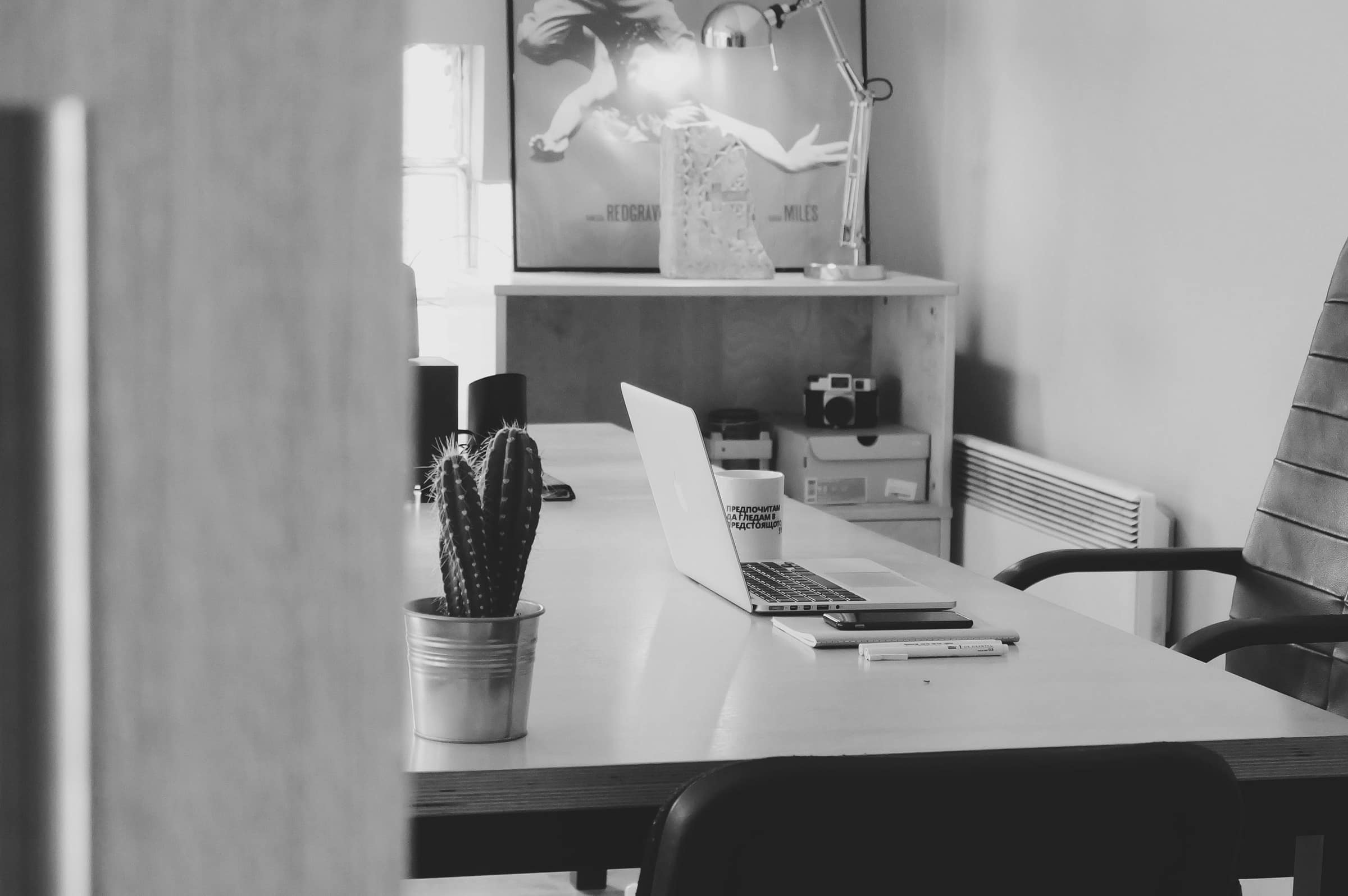 A single desk with an open laptop and an empty chair pushed back